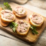 Pate produced via food technology such as ohmic heating, shear-cell technology and high moisture extrusion. The pate is on round slices of bread, which are served on top of a chopping board with herbs