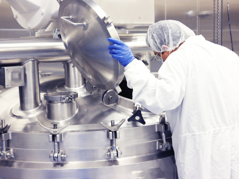 A scientist in a clean room inspecting the inside of a bioreactor (otherwise known as a cultivator), where cultivated meat is being made